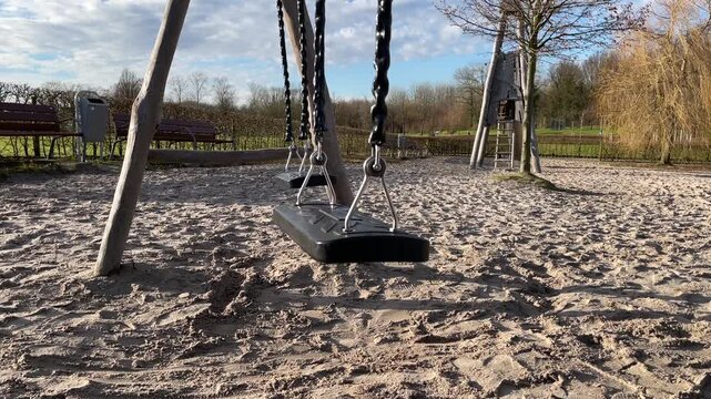 Empty Swing Gently Swinging in Children Playground Close Up