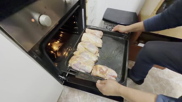 Chef placing marinated pork knuckle on baking tray into the oven for roasting