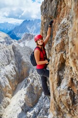 Obraz premium Woman enjoying via ferrata climbing in dolomites mountains
