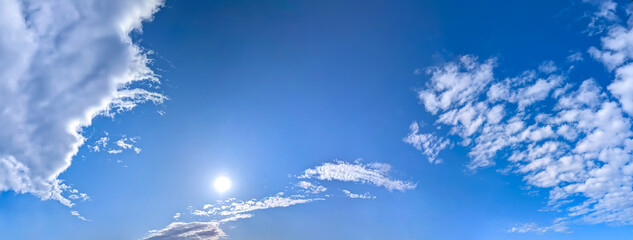A panorama of cumulus clouds against a blue sky. A summery, serene landscape. The cloud's smooth movement copy space for banner text. Clear background with tiny white fluffy cloud. © codexserafinius