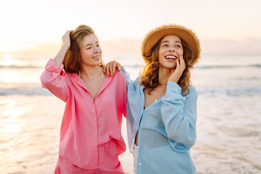 Two friends are having fun on the beach on a sunny day. Beautiful friends are spending time together, enjoying the seascape at sunset. Concept of friendship, nature, and vacation.