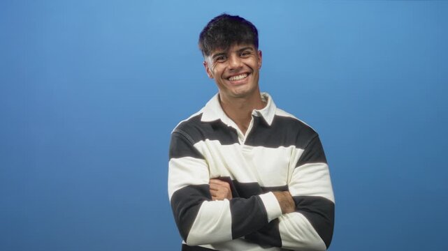 Man in black and white striped rugby shirt smiling with arms crossed facing camera in studio under soft light; confidence.