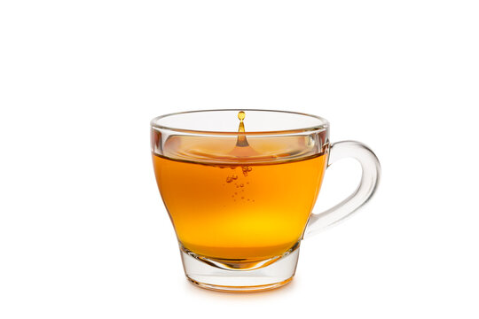 Glass cup of tea with splashing droplet isolated on white background.