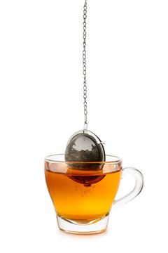 Glass cup of tea with metal tea infuser inside, isolated on white background.