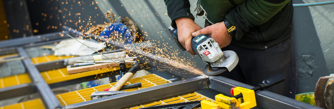Craftsman skillfully operates an angle grinder, fabricating a metal structure