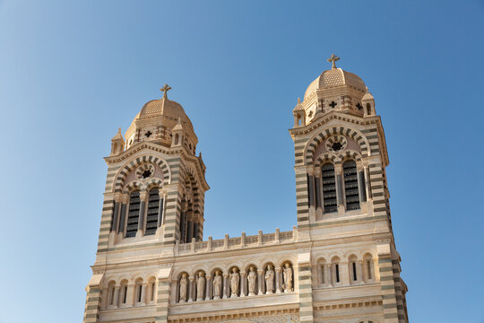 D&eacute;tail de la fa&ccedil;ade d'entr&eacute;e de la Cathédrale de La Major &agrave; Marseille, vue en contre-plong&eacute;e des deux tours clochers avec coupoles, fronton du porche avec des statues de Saints, ciel bleu en fond