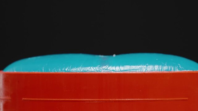 Close-up of a blue deodorant retracting into a red container, focusing on the smooth surface and functionality of the product, showcasing personal care design and usability