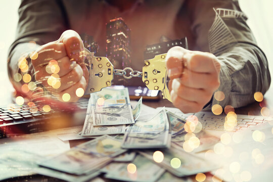  Double exposure city and hands of a man with handcuffs on a background of us dollars. Fraud, cyber crime concept. Arrest of an entrepreneur in the workplace.