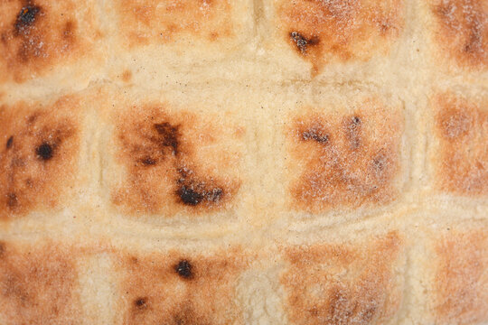 A detailed close-up view shows the golden brown grid pattern and floury texture on the surface of a traditional baked flatbread