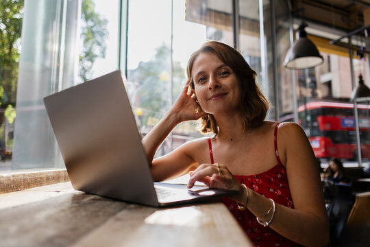 Freelancer working on laptop by window in London cafe with bus outside