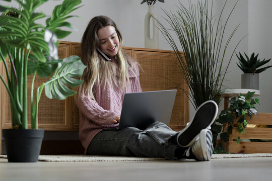 Woman multitasking with laptop and phone while working from home