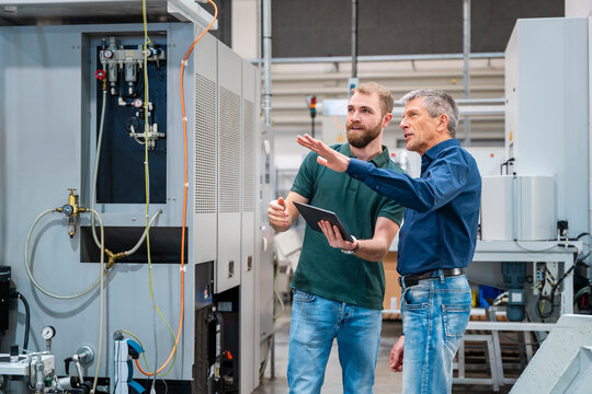 Two men discussing in a production hall with a tablet