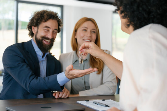 Real estate agent giving keys to clients after new house contract signing