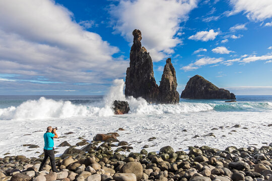 Tourist taking photo of sea stacks at Ilh�us da Ribeira da Janela Madeira
