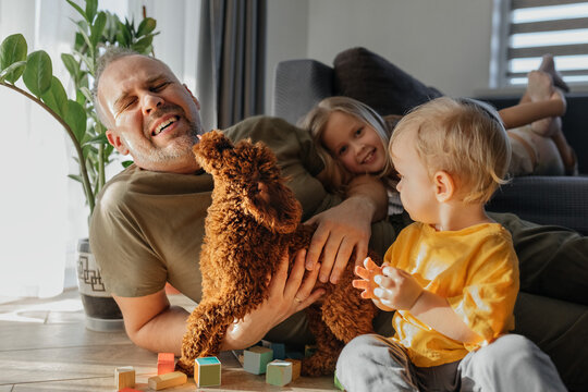 Father playing with children and small dog in pet friendly home