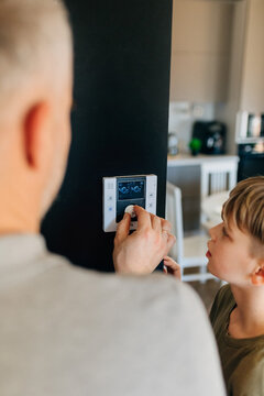 Parent teaching child home heating control on smart thermostat