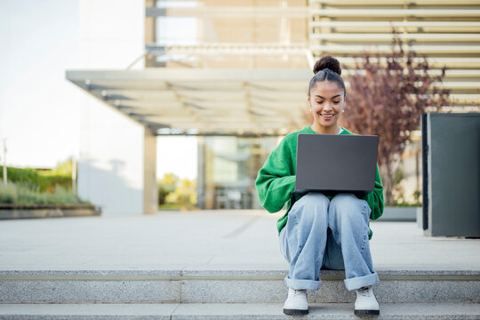 Student using laptop for studying outdoors on university campus