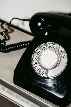 Vintage black rotary dial telephone close up on desk with flash