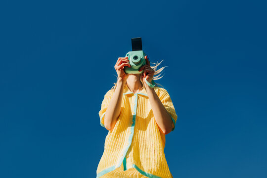 Fashionable woman taking photo with retro camera outdoors in spring