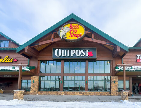 Calgary, Alberta, Canada. April 1, 2026. Exterior entrance of a Bass Pro Shops Outpost and Cabela's retail store featuring rustic architecture.