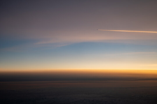 An airplane leaves a contrail in the sky above China's Qilian Mountains during a sunset