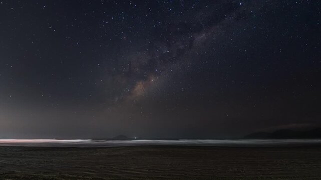 Milky Way galaxy shining over a serene ocean beach at night time lapse nightscape