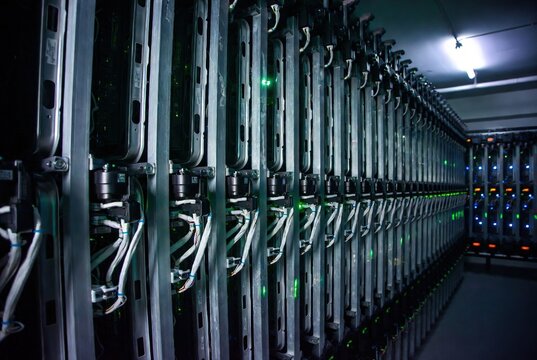 Extensive rows of active server racks with vibrant green indicator lights in a modern data center environment