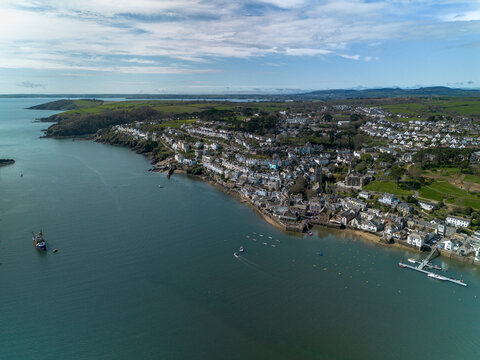 Wide aerial view of the Fowey estuary opening into the sea in Cornwall, UK. Expansive blue water and sky with the town of Fowey along the shoreline, ideal for travel and background use.