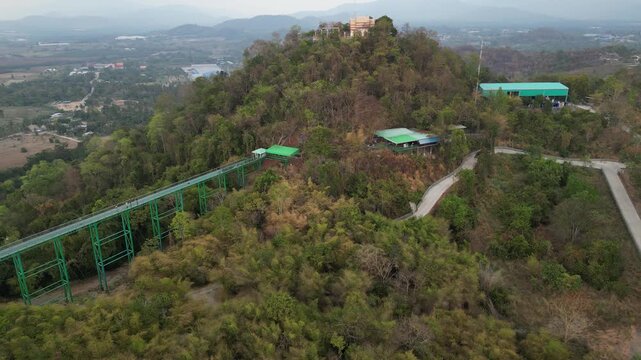 태국 왓 타백 사찰의 거대한 불상과 숲 위를 가로지르는 현대적인 스카이워크 브릿지
