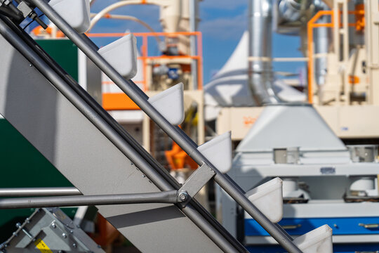 Bucket elevator conveyor system for industrial grain handling and agricultural seed transport, close up of plastic buckets on a belt at a processing facility