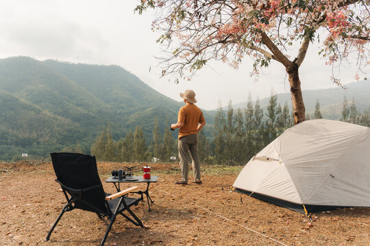 Solo man camping with tent and coffee overlooking mountain valley in countryside