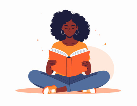 Young Black woman with afro reading a book while sitting cross-legged