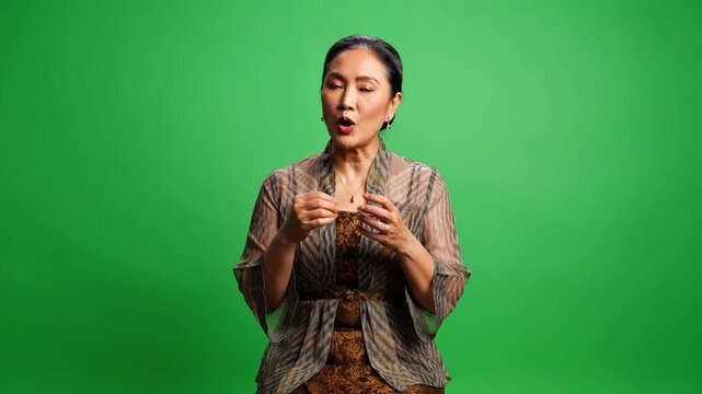 Asian woman gesturing on green screen.