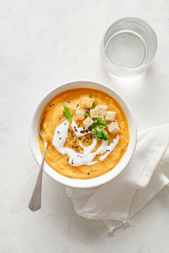 Bowl with pumpkin cream on a light background.