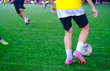 Fototapeta premium Young soccer player dribbling the ball during a friendly match on indoor field, action moment with blurred background, concept of youth football competition and teamwork.