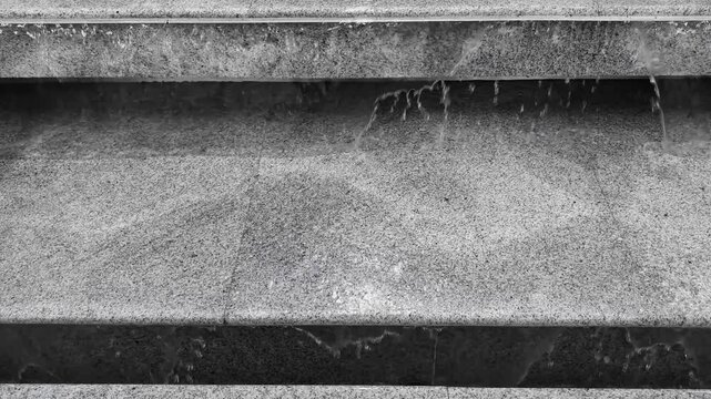 Water is flowing down the steps. Steps made from stone show patterns and textures in urban setting with views up and down