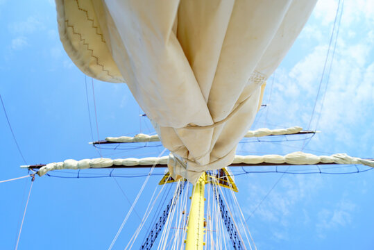Upward view of tall mast and complex rigging with folded sails against sky. Reveals historic seamanship practices, wind-powered travel heritage, and classic square-rigger sailing craft on open waters.