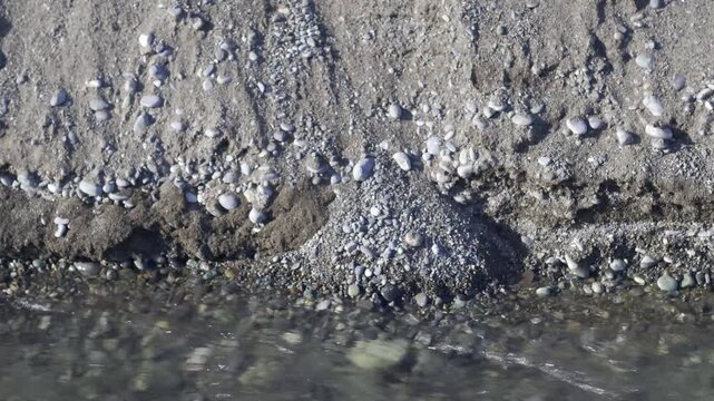 River stream eroding pebble beach and flowing into the sea