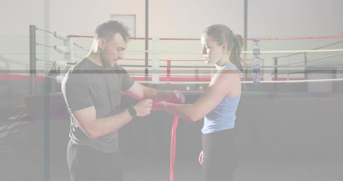 Trainer feeding red hand wrap and winding around trainee hand in boxing ring, securing for sparring