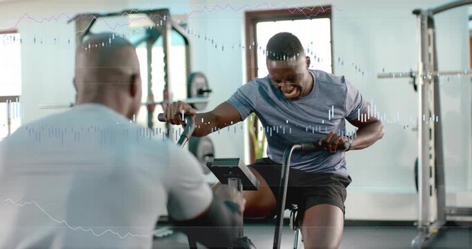 Trainee sprinting on air bike on coach cue, powering pedals with pulse graphs rising for fitness