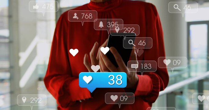 Woman in red blouse holding black smartphone tapping screen in glass atrium, with blue 38 icons