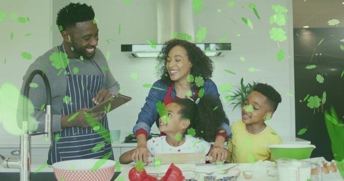 Gathering family of four preparing food at kitchen island, wearing striped apron and holding tablet