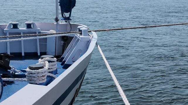 Boat sails on calm water with rope and equipment in view