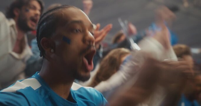 Portrait of a Young Black Male Supporter in a Blue Jersey Cheering With a Smiling Crowd in a Packed Stadium During a Professional Soccer League Match, Celebrating a Major International Cup Moment.