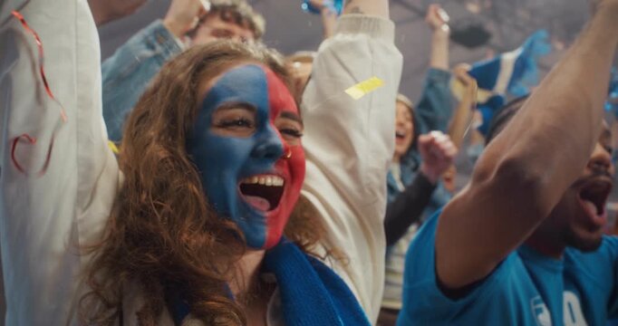 Close-up of Jubilant Football Supporters in a Packed Stadium as a Young White Woman With Blue and Red Face Paint Laughs and Cheers Beside Black Fans During a Major International League Cup Match.