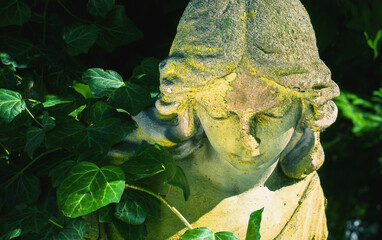 Fototapeta premium Guardian angel statue surrounded by green leaves, symbolizing protection, care, and spiritual comfort in a peaceful natural environment.