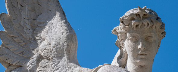 Fototapeta premium Angel with wings against blue sky, symbolizing soul transition, afterlife, and spiritual passage between worlds in a conceptual composition.