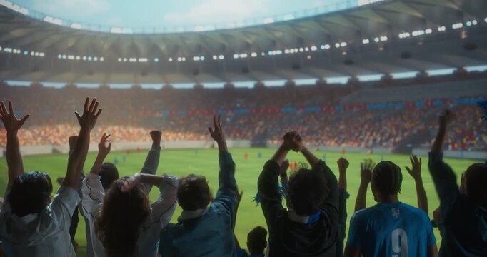 Back view Soccer Supporters Celebrate in a Packed Stadium, Raising Arms and Clapping During a Professional International Championship Match Game at a Major World Tournament Event