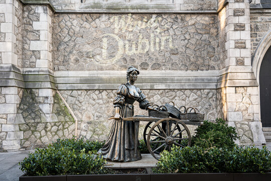 Landscape shot of Molly Malone statue in Dublin, Ireland with stone textured wall behind on sunny winters day