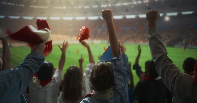 Rear View of Diverse Soccer Supporters Celebrating in Big Stadium, Raising hands, Waving Scarves and Cheering With Victory Spirit During a International Championship Match on Field. Slow Motion